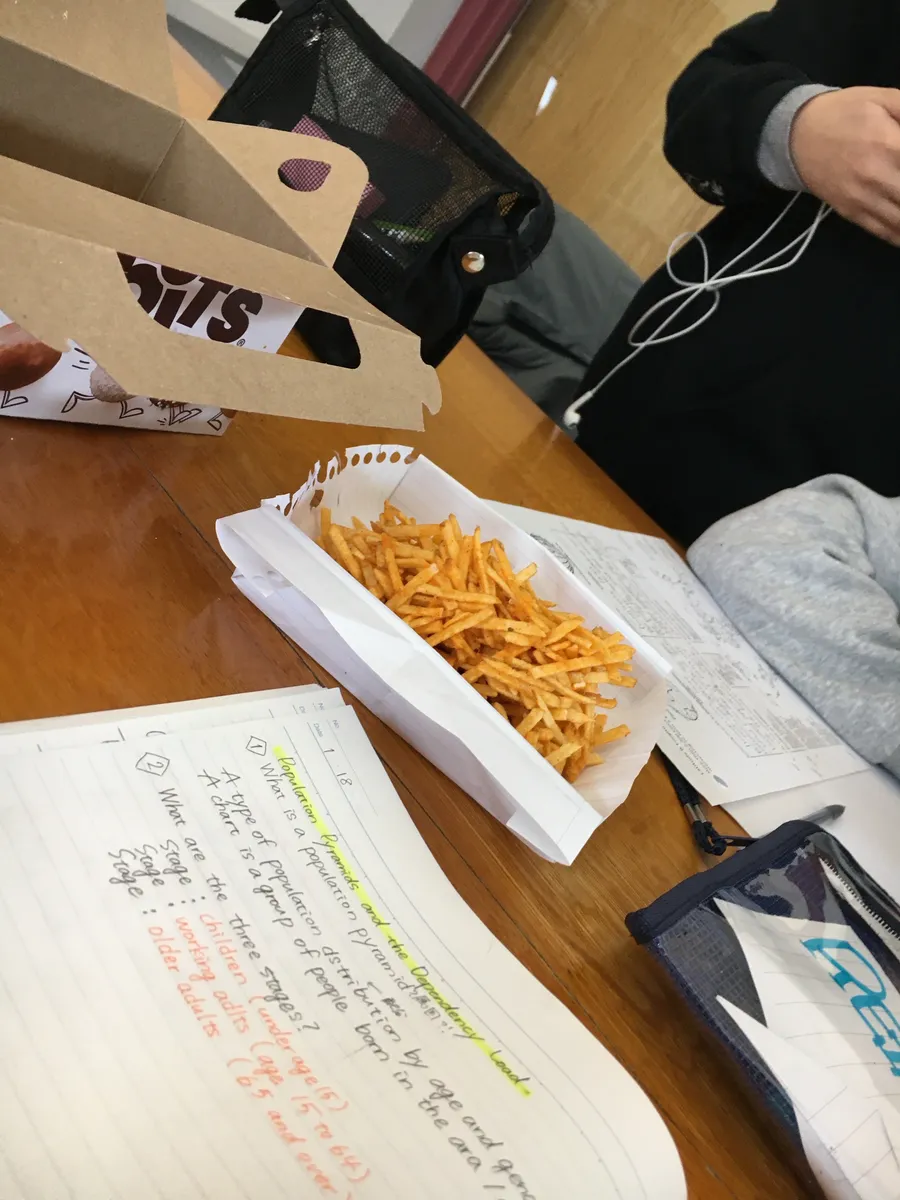 フライドポテトをつまみながらノートを広げてテスト勉強をする様子