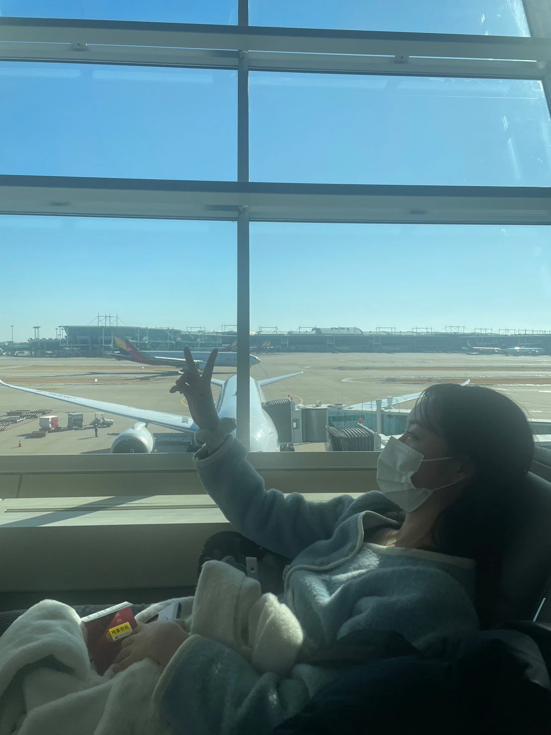 空港のラウンジで飛行機に向かって手を振るりんさん
