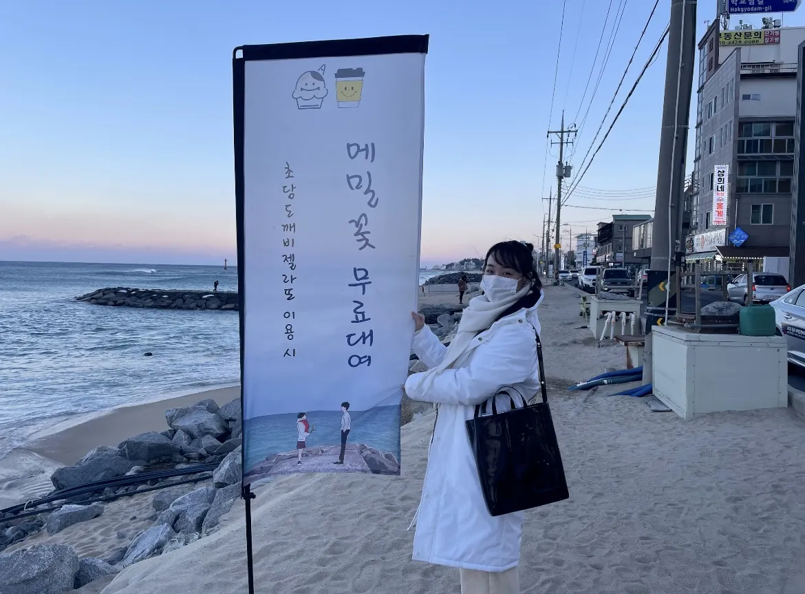 『トッケビ』の撮影地を示すのぼりの前に立つりんさん